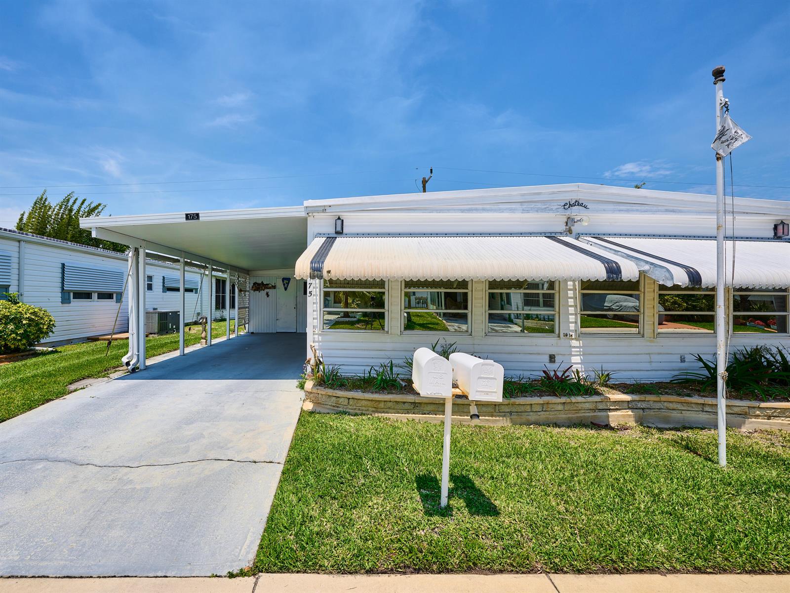A white mobile home features a carport, a striped awning, and two mailboxes on the lawn — 4300 SE Saint Lucie Boulevard # 175, Stuart FL 34997, STUART, FL