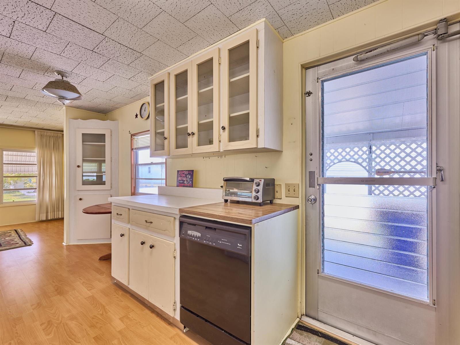 A kitchen features light-colored cabinets, a black dishwasher, a toaster oven, and a screen door — 4300 SE Saint Lucie Boulevard # 175, Stuart FL 34997, STUART, FL