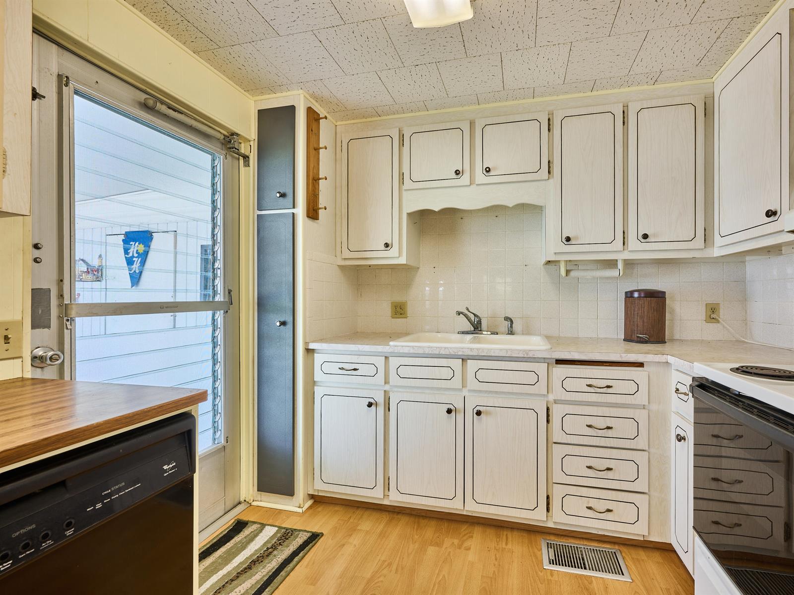 A kitchen features white cabinets with dark trim, a double sink, and a screen door — 4300 SE Saint Lucie Boulevard # 175, Stuart FL 34997, STUART, FL