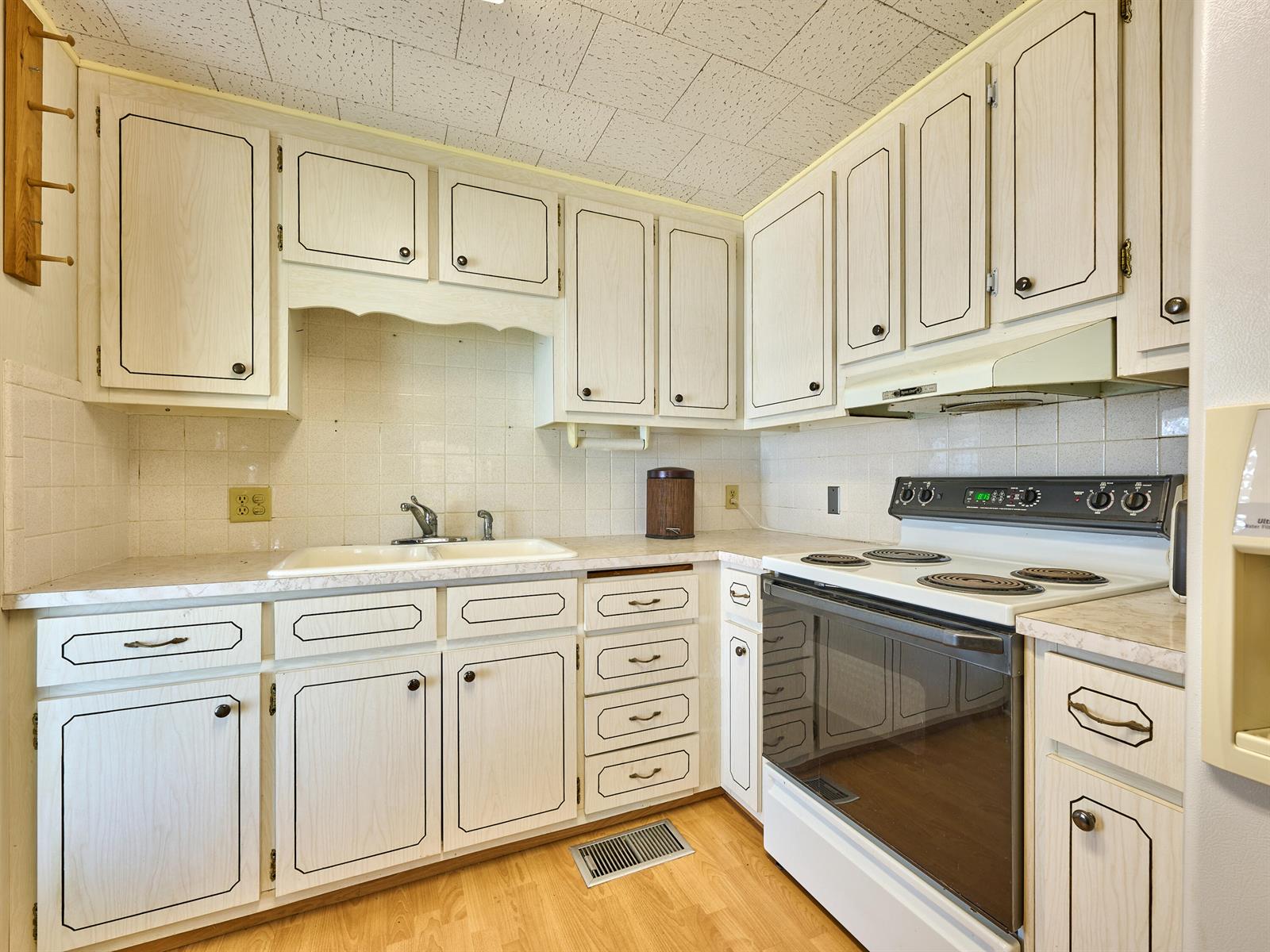 A kitchen features white cabinets with dark trim, a white stove, and a double sink — 4300 SE Saint Lucie Boulevard # 175, Stuart FL 34997, STUART, FL