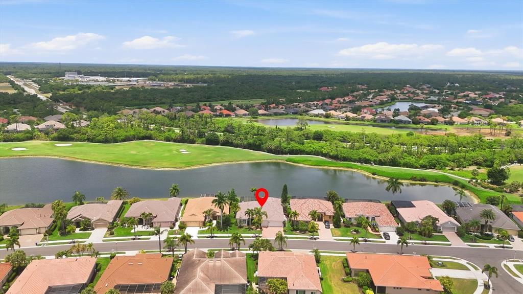 An aerial view shows a suburban neighborhood with houses bordering a lake and golf course — 5184 WHITE IBIS DRIVE, NORTH PORT, FL