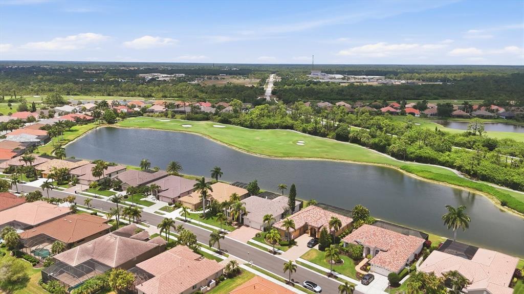 An aerial view shows a residential neighborhood with houses bordering a lake and golf course — 5184 WHITE IBIS DRIVE, NORTH PORT, FL