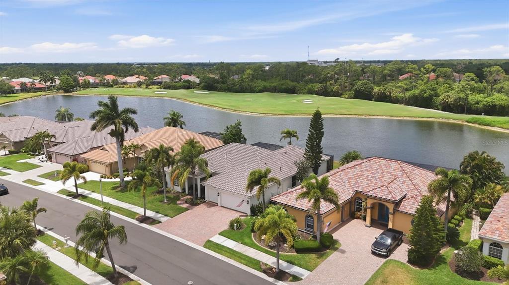 An aerial view shows several houses with tile roofs situated along a lake and golf course — 5184 WHITE IBIS DRIVE, NORTH PORT, FL