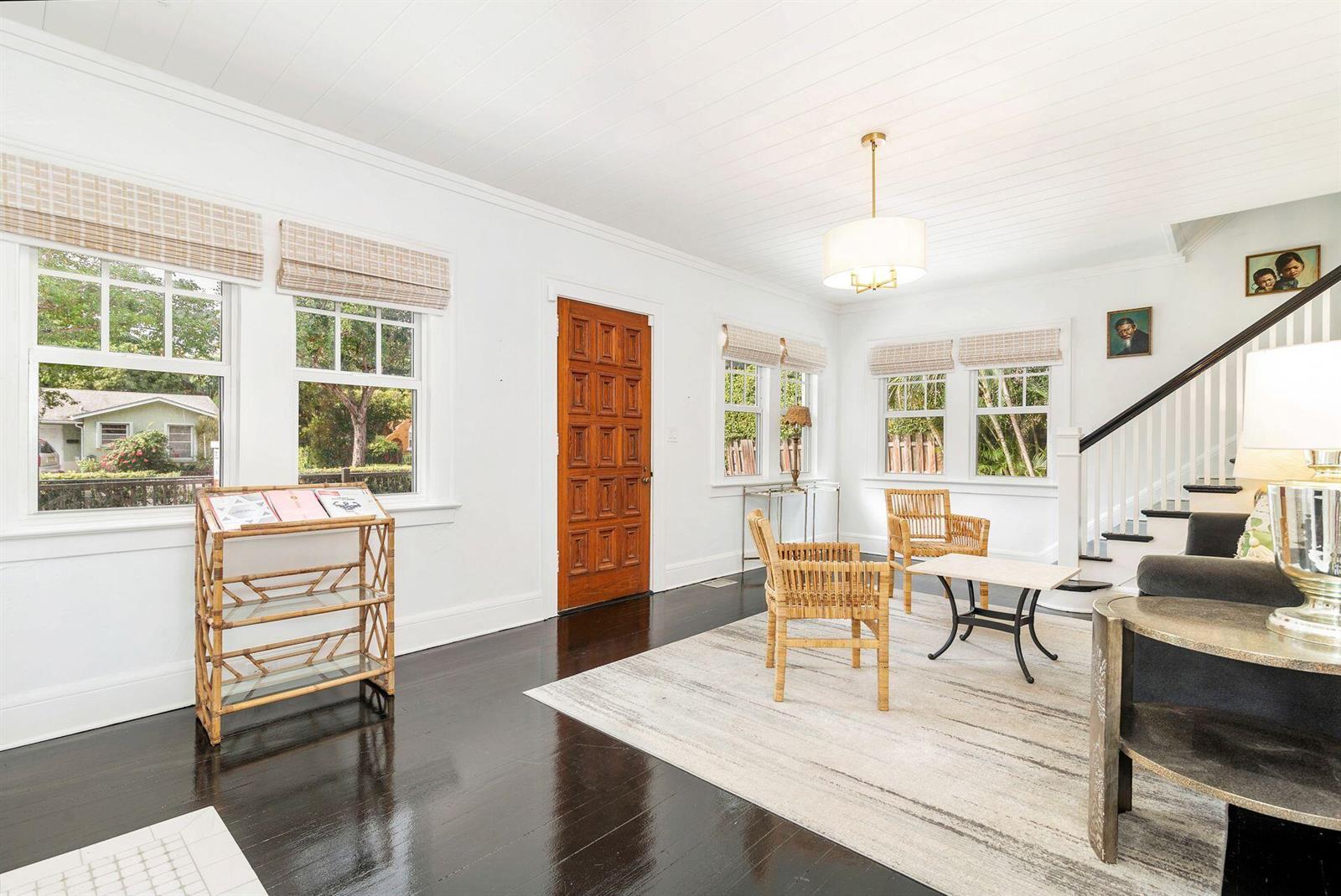A bright living room features dark hardwood floors, white walls, a wooden door, and rattan furniture — 3504 S Olive Avenue, West Palm Beach FL 33405, WEST PALM BEACH, FL