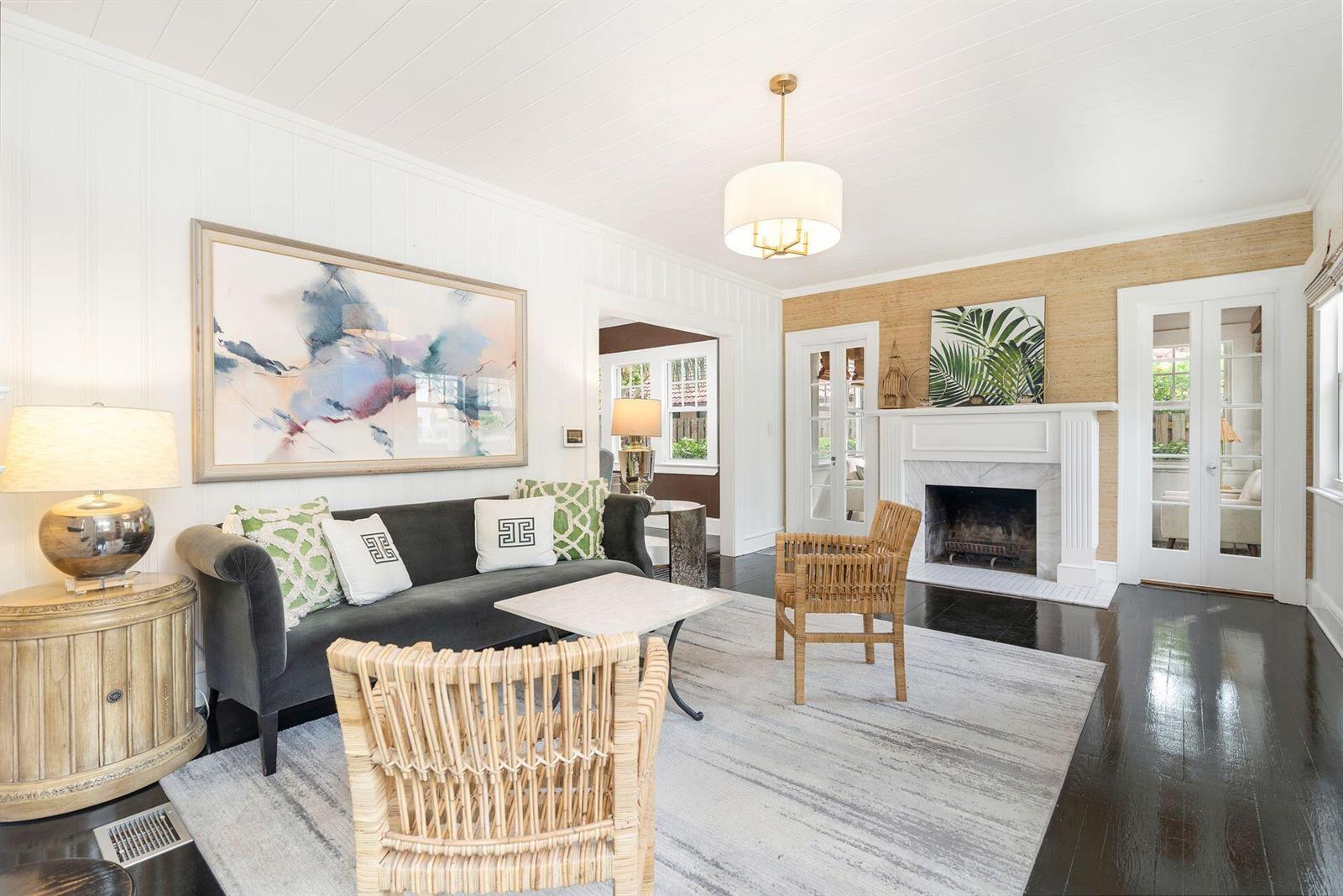 A living room features a dark sofa, wicker chairs, a fireplace, and white paneled walls — 3504 S Olive Avenue, West Palm Beach FL 33405, WEST PALM BEACH, FL