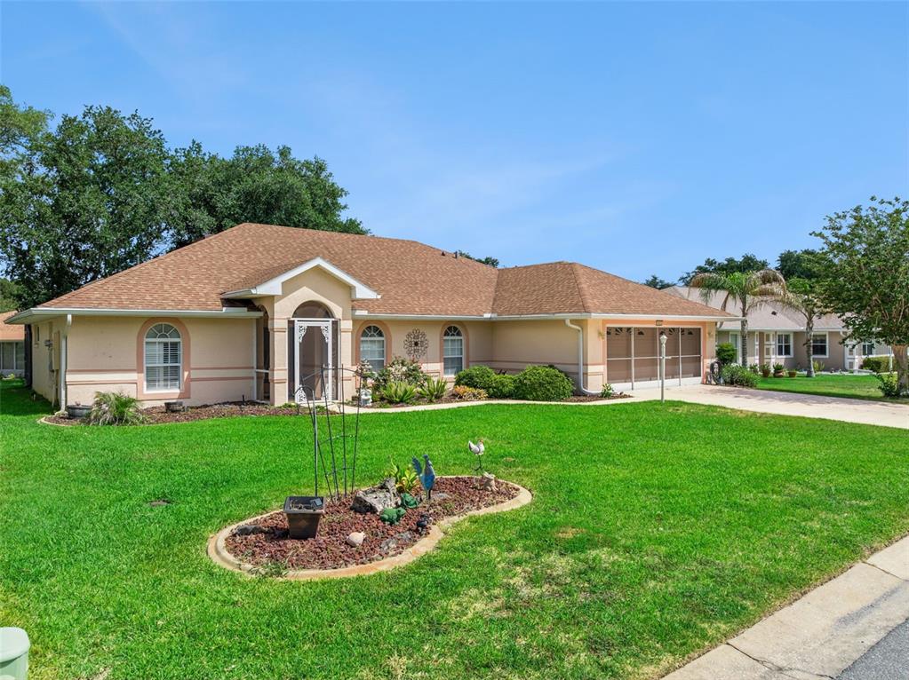 A single-story house with a tan exterior, arched entryway, and a screened-in garage — 5825 PRINCESS CAROLINE PLACE, LEESBURG, FL
