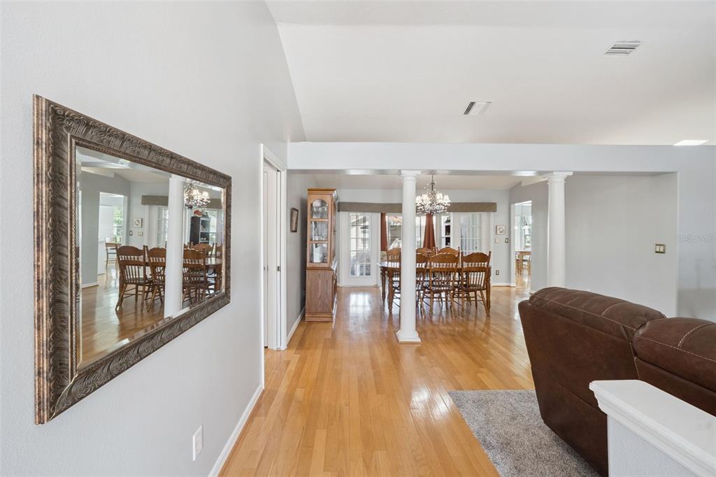 A dining area with a wooden table and chairs is visible through a living room — 5825 PRINCESS CAROLINE PLACE, LEESBURG, FL