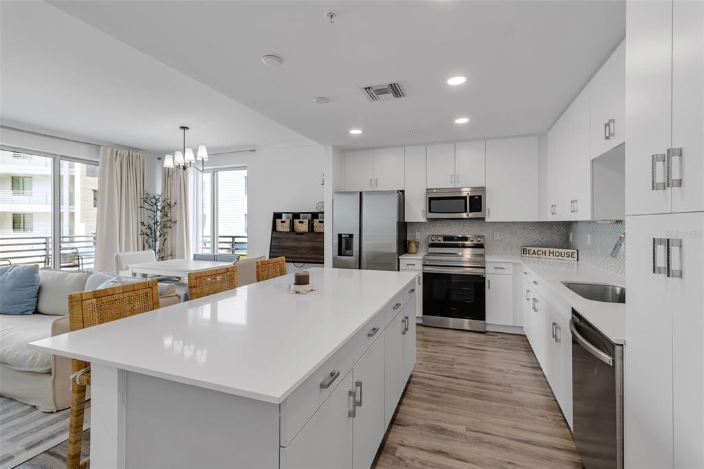 A modern kitchen features white cabinets, stainless steel appliances, and a large central island — 1703 N TAMIAMI TRAIL UNIT 211, SARASOTA, FL