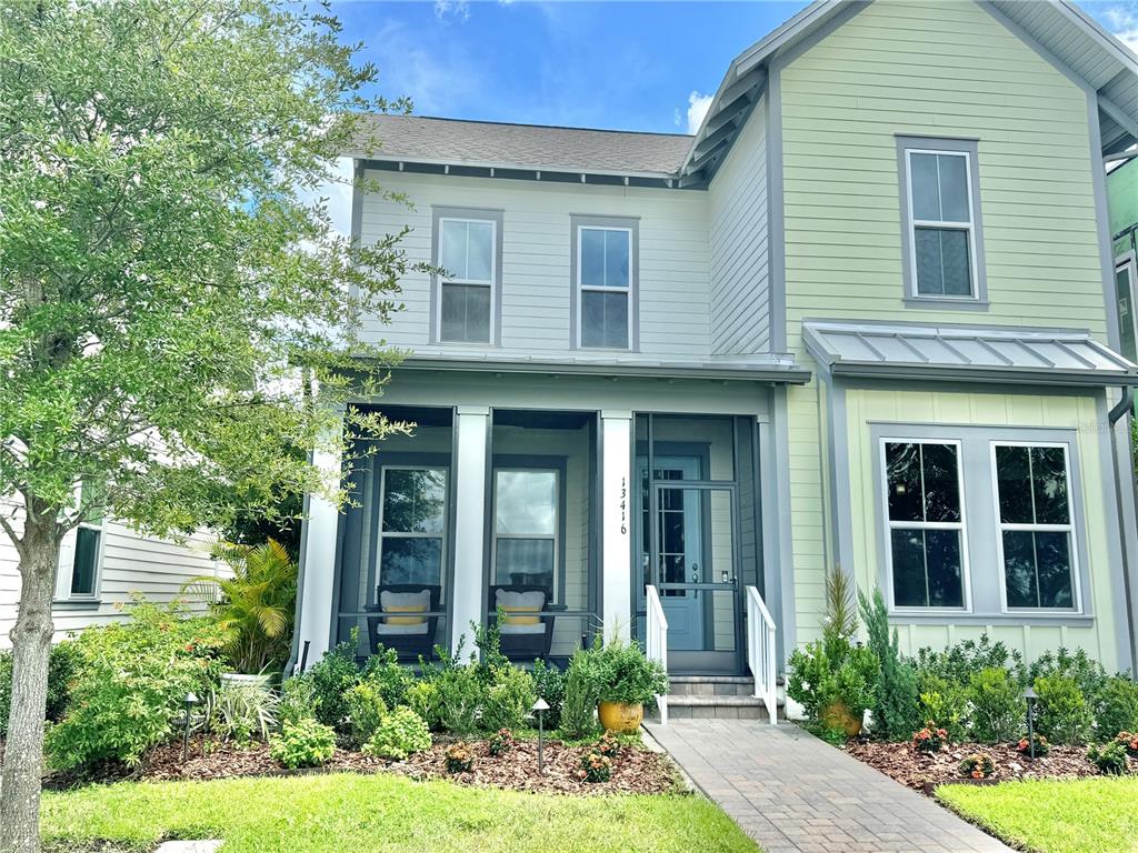 A two-story house with a screened front porch, light-colored siding, and a paved walkway — 13416 BEEBE ALLEY, ORLANDO, FL