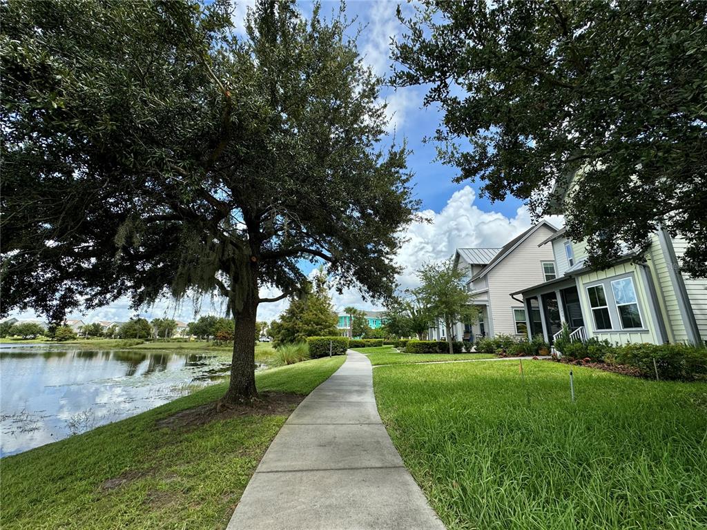 A sidewalk leads past a large tree and a pond toward a suburban house — 13416 BEEBE ALLEY, ORLANDO, FL