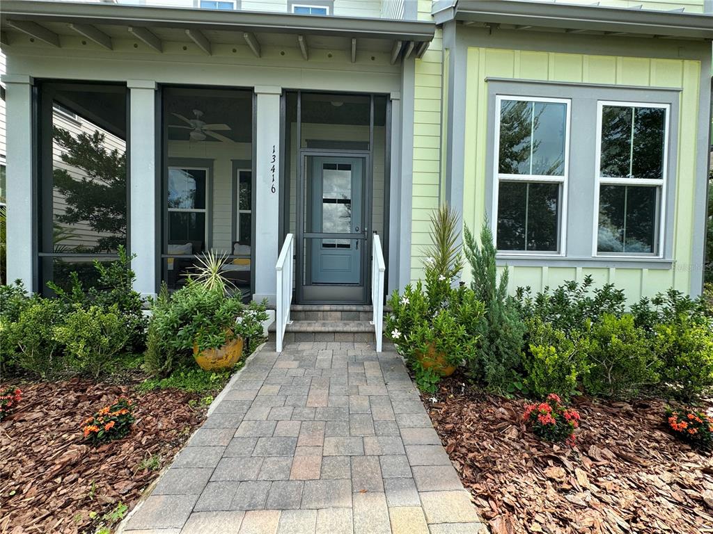 A paved walkway leads to the screened front porch and blue door of a house — 13416 BEEBE ALLEY, ORLANDO, FL