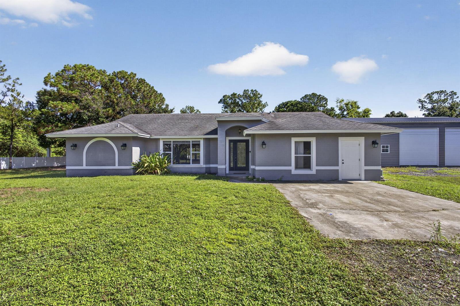 A single-story gray house with a concrete driveway and an adjacent detached garage — 14935 89th Place N, Loxahatchee FL 33470, LOXAHATCHEE, FL