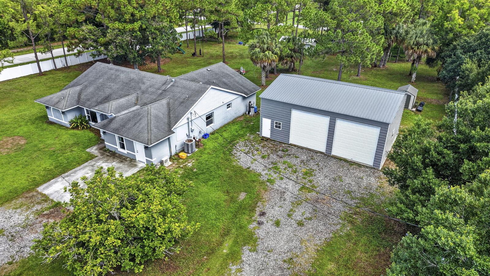 An aerial view shows a house with a gray roof next to a detached metal garage — 14935 89th Place N, Loxahatchee FL 33470, LOXAHATCHEE, FL