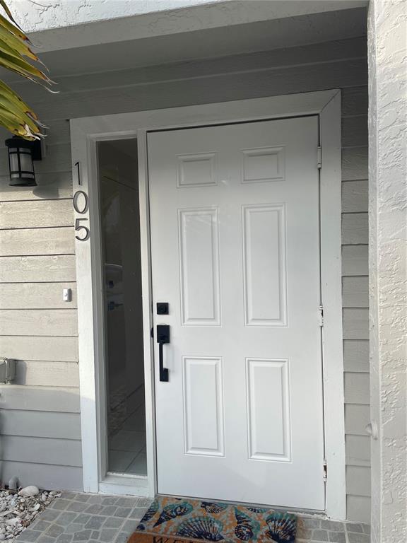 A white six-panel front door with a side window and house number 105 — 745 PINELLAS BAYWAY S UNIT 105, ST PETERSBURG, FL