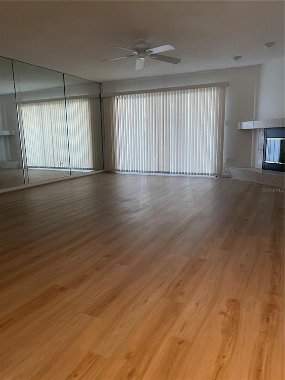 A living room features light wood flooring, a mirrored wall, vertical blinds, and a fireplace — 745 PINELLAS BAYWAY S UNIT 105, ST PETERSBURG, FL
