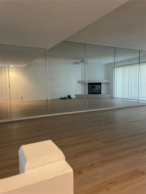 A living room features light wood flooring and a wall covered in large, floor-to-ceiling mirrors — 745 PINELLAS BAYWAY S UNIT 105, ST PETERSBURG, FL
