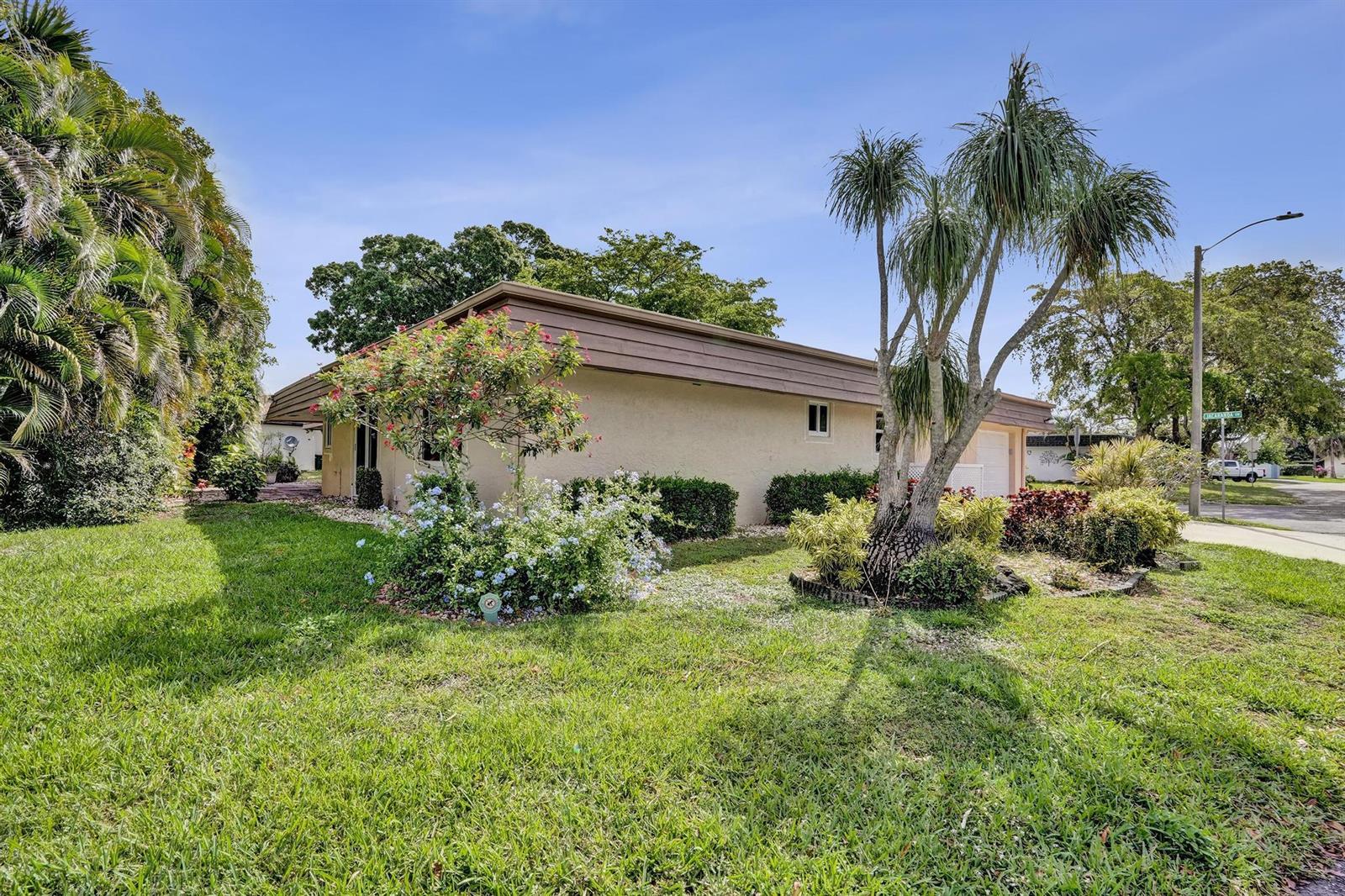 A single-story house with a tan exterior, a brown roofline, and a palm tree in front — 6207 Jacaranda Circle, Tamarac FL 33319, TAMARAC, FL