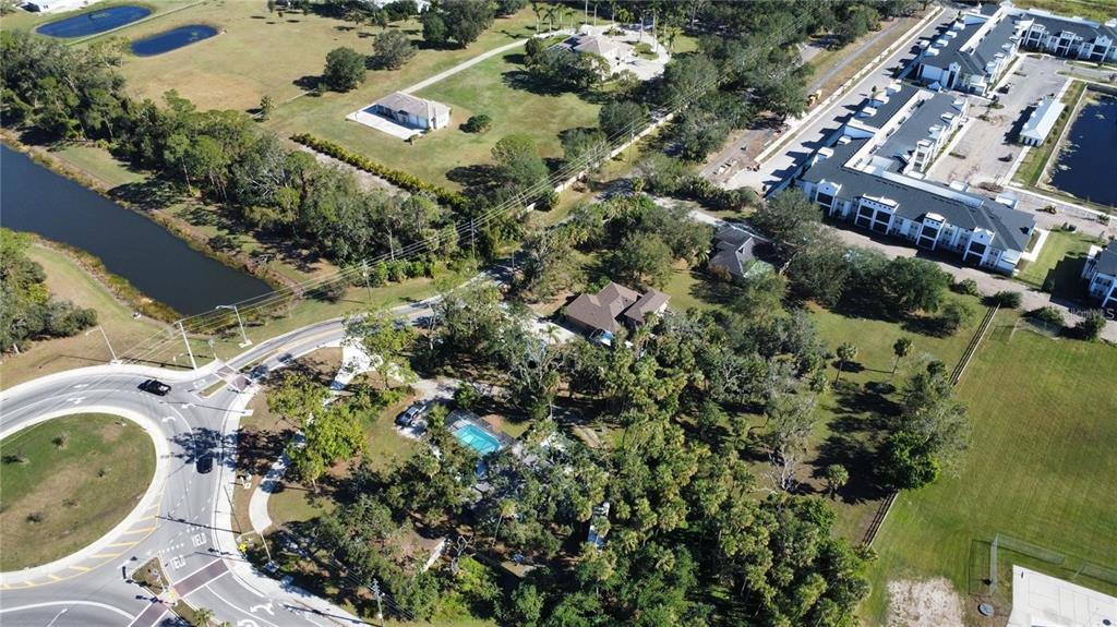 An aerial view shows a residential property with a pool, surrounding trees, and nearby apartment buildings — 6500 RICHARDSON ROAD, SARASOTA, FL