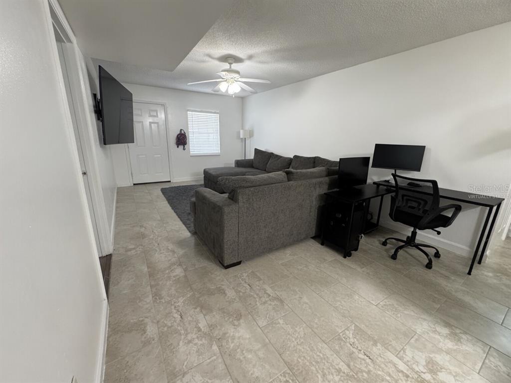 A living room features tile flooring, a gray sectional sofa, and a computer desk area — 31 DEACON JONES BOULEVARD UNIT A & B, ORLANDO, FL