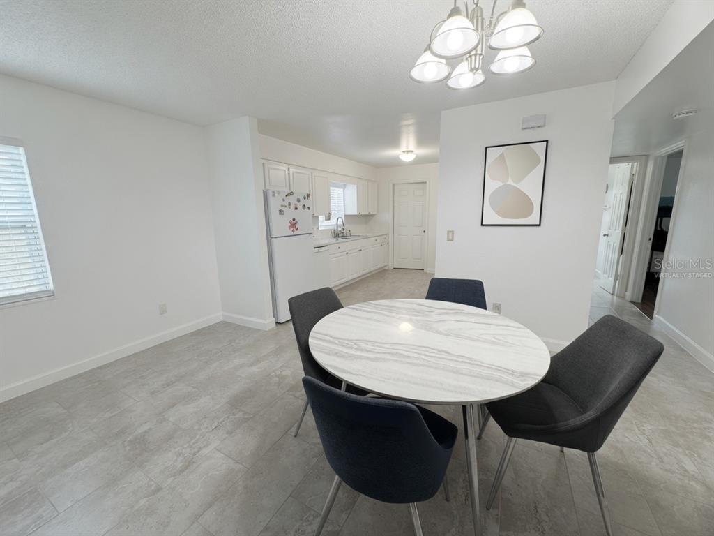 A dining area with a round table and chairs sits adjacent to a white kitchen — 31 DEACON JONES BOULEVARD UNIT A & B, ORLANDO, FL