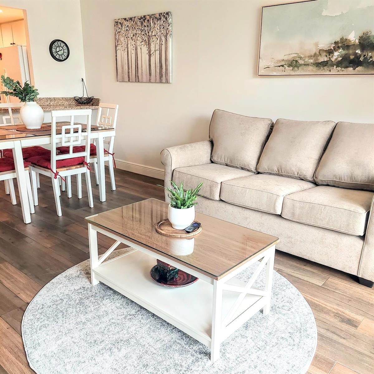 A living room features a beige sofa, a glass-top coffee table, and a dining area — 1830 Embassy Drive # 306, West Palm Beach FL 33401, WEST PALM BEACH, FL