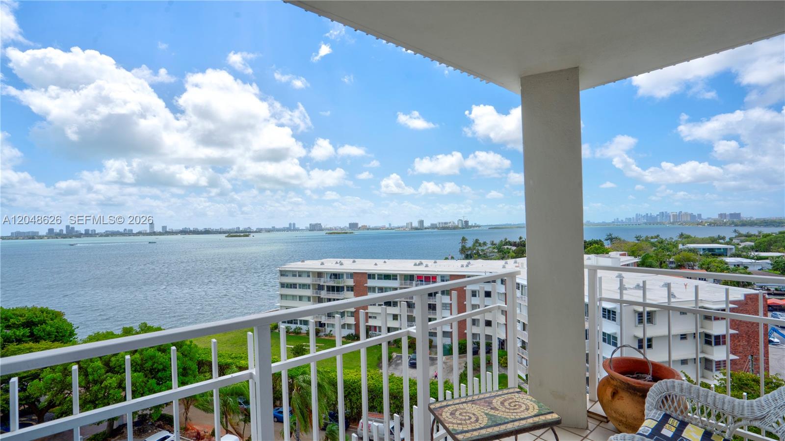 A balcony overlooks a bay with a view of distant city skylines and buildings — 4000 Towerside Ter # 908, Miami FL 33138, MIAMI, FL