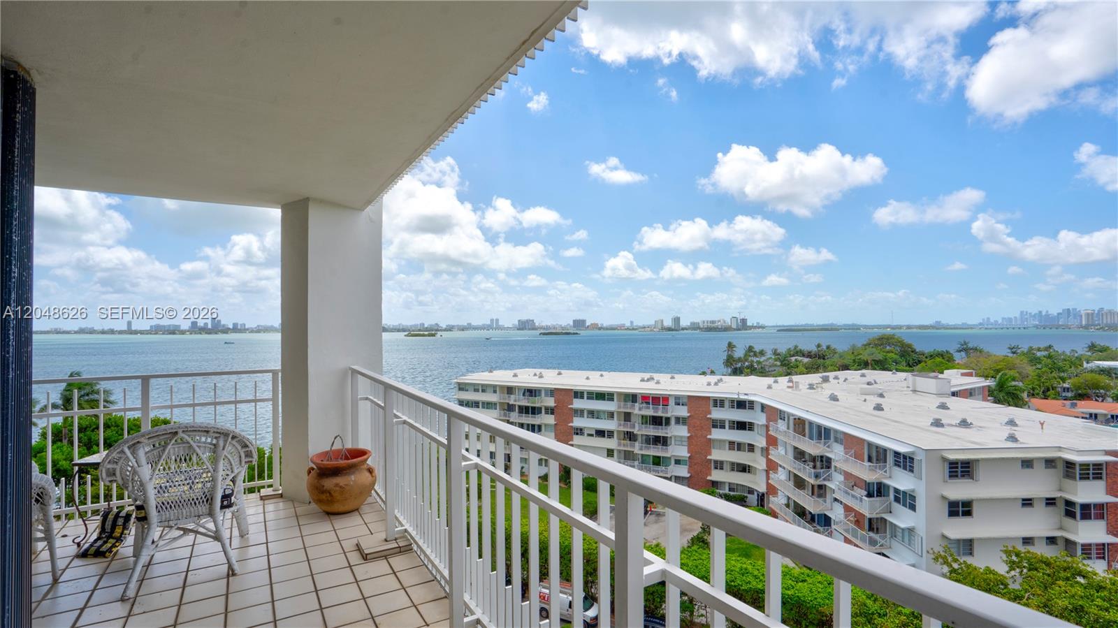 A balcony with a white railing overlooks a bay and a nearby apartment building — 4000 Towerside Ter # 908, Miami FL 33138, MIAMI, FL