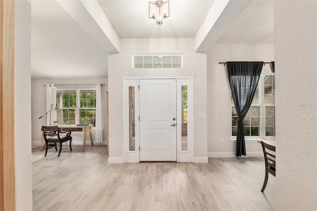 A bright entryway with light wood-look tile flooring, a white front door, and side windows — 8179 NE 8TH PLACE, HIGH SPRINGS, FL