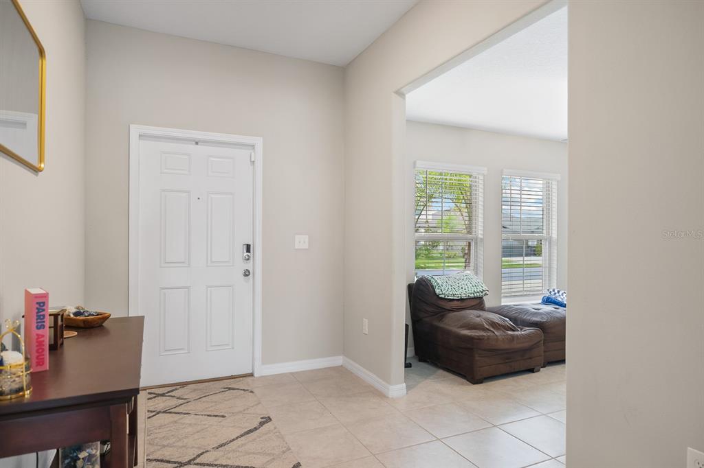 An entryway with tile flooring leads to a living area with a brown leather chair — 16640 CARLTON POND STREET, WIMAUMA, FL