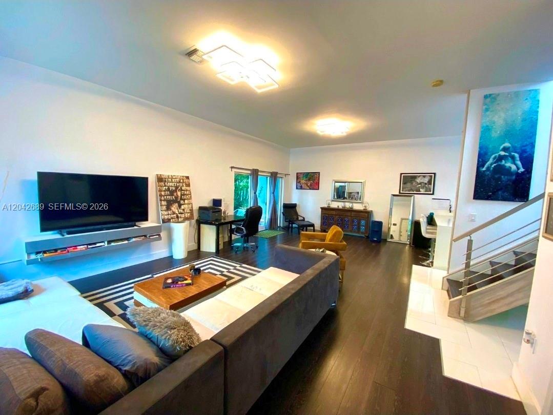A living room features dark wood floors, a large television, and a staircase — 2732 SW 26 St # 2732, Miami FL 33133, MIAMI, FL