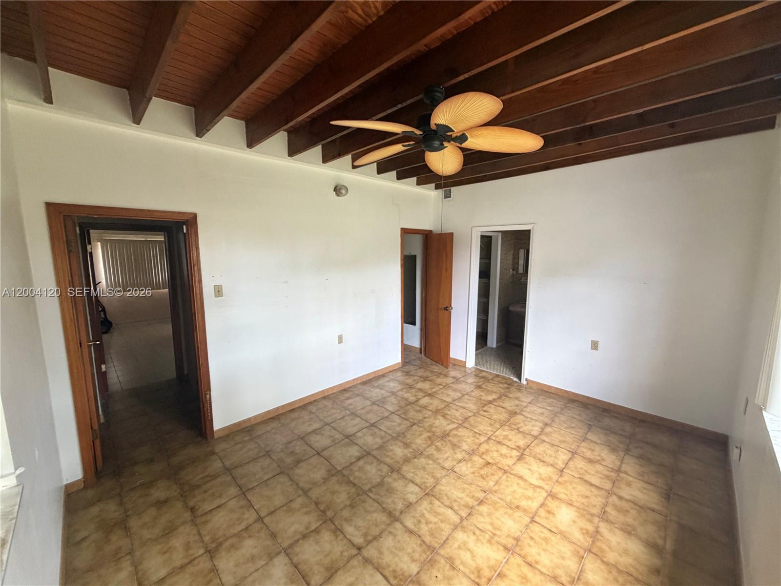 A room with a wood-beamed ceiling, tile flooring, a ceiling fan, and two doorways — 10910 SW 40th St, Miami FL 33165, MIAMI, FL