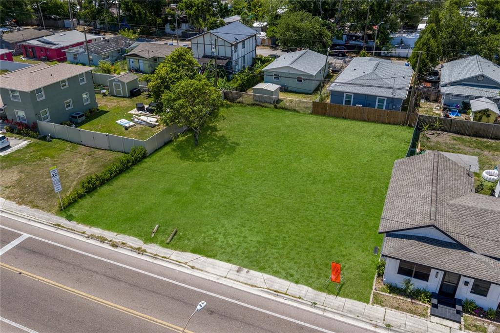 An aerial view shows a vacant, grassy rectangular lot situated between two residential houses — 15TH AVENUE S, ST PETERSBURG, FL
