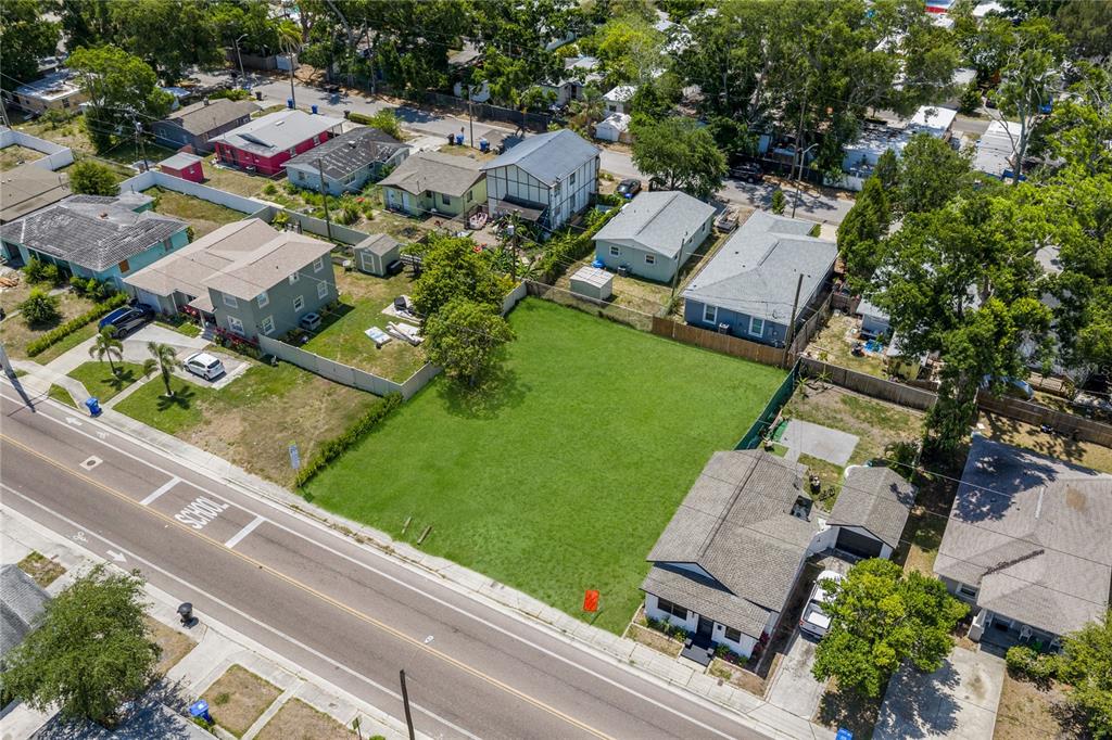 An aerial view shows a vacant grassy lot situated between several residential houses and a road — 15TH AVENUE S, ST PETERSBURG, FL