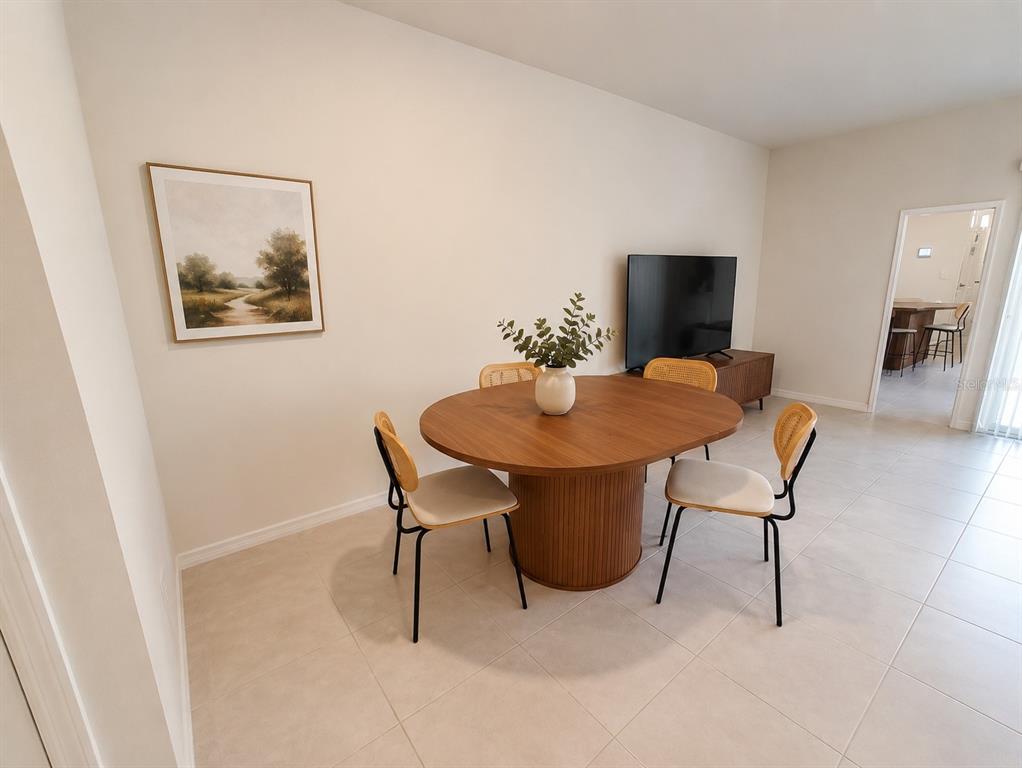 A dining area features a round wooden table with four chairs and a television console — 2393 PENGUIN BOULEVARD, DAVENPORT, FL