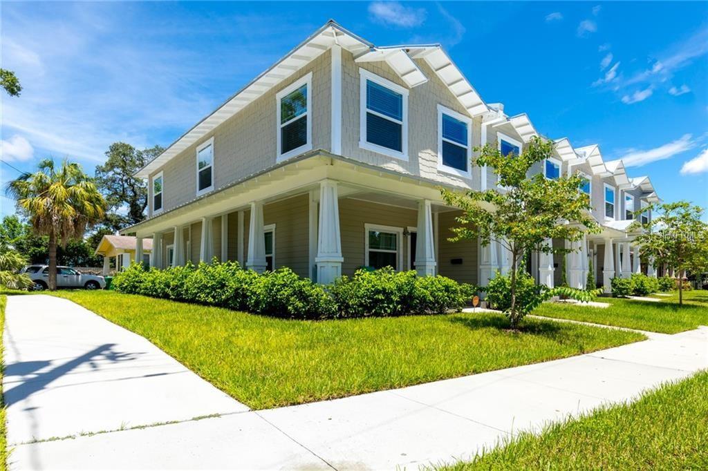 A two-story townhouse with a wrap-around porch, light siding, and a manicured lawn — 121 W GIDDENS AVENUE, TAMPA, FL