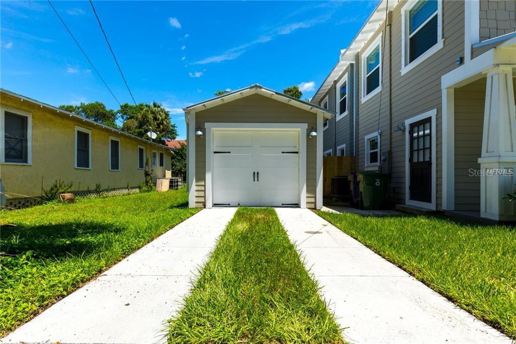 A detached garage sits at the end of a concrete driveway between two houses — 121 W GIDDENS AVENUE, TAMPA, FL