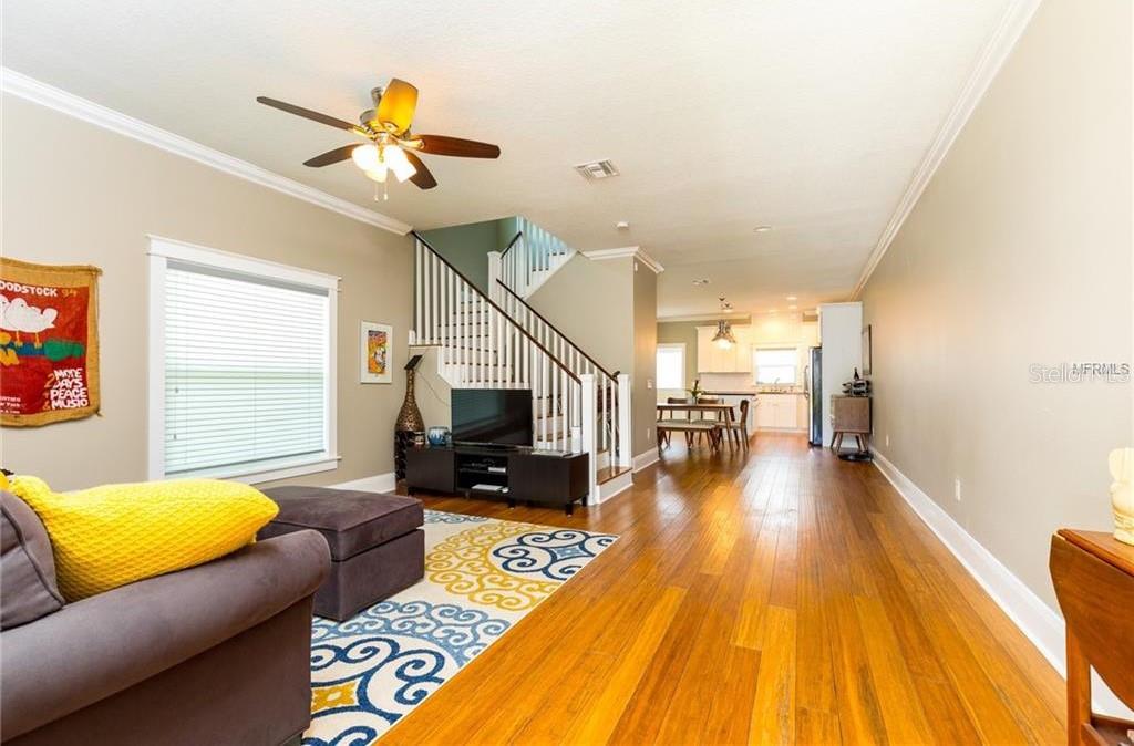 A living room with hardwood floors, a staircase, and an open view to the kitchen — 121 W GIDDENS AVENUE, TAMPA, FL