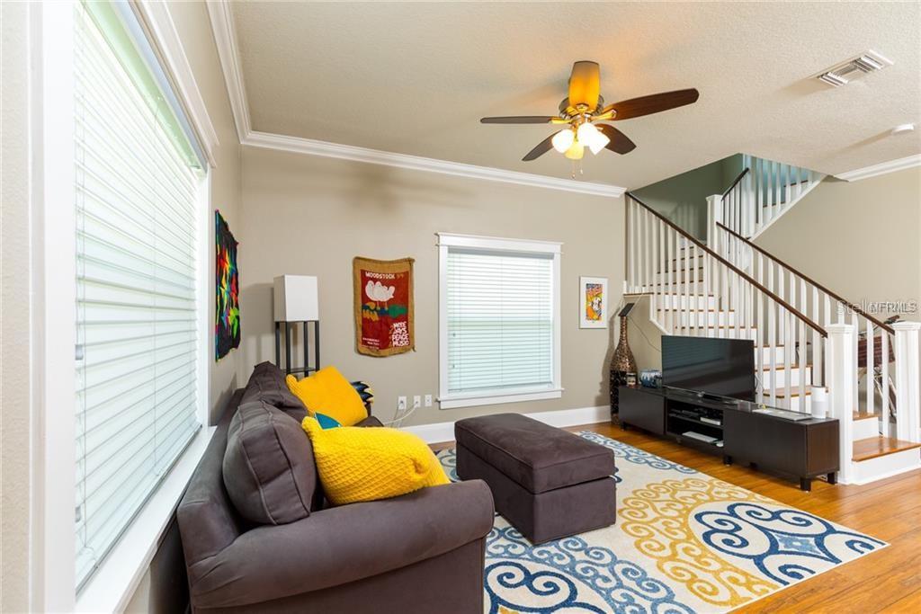 A living room features a grey sofa, a patterned rug, and stairs leading to an upper level — 121 W GIDDENS AVENUE, TAMPA, FL