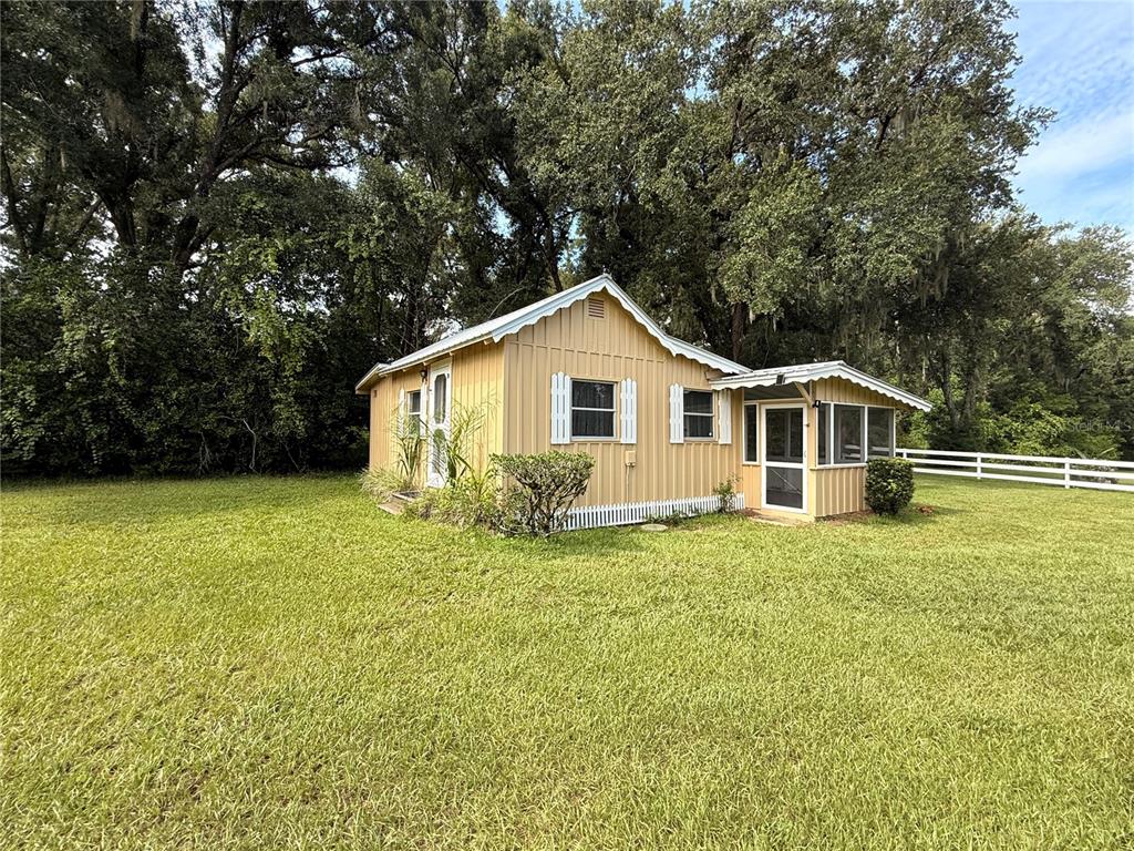 A yellow, single-story farmhouse with a wrap-around porch sits on a grassy rural lot — 34951 EASTERLING ROAD, DADE CITY, FL
