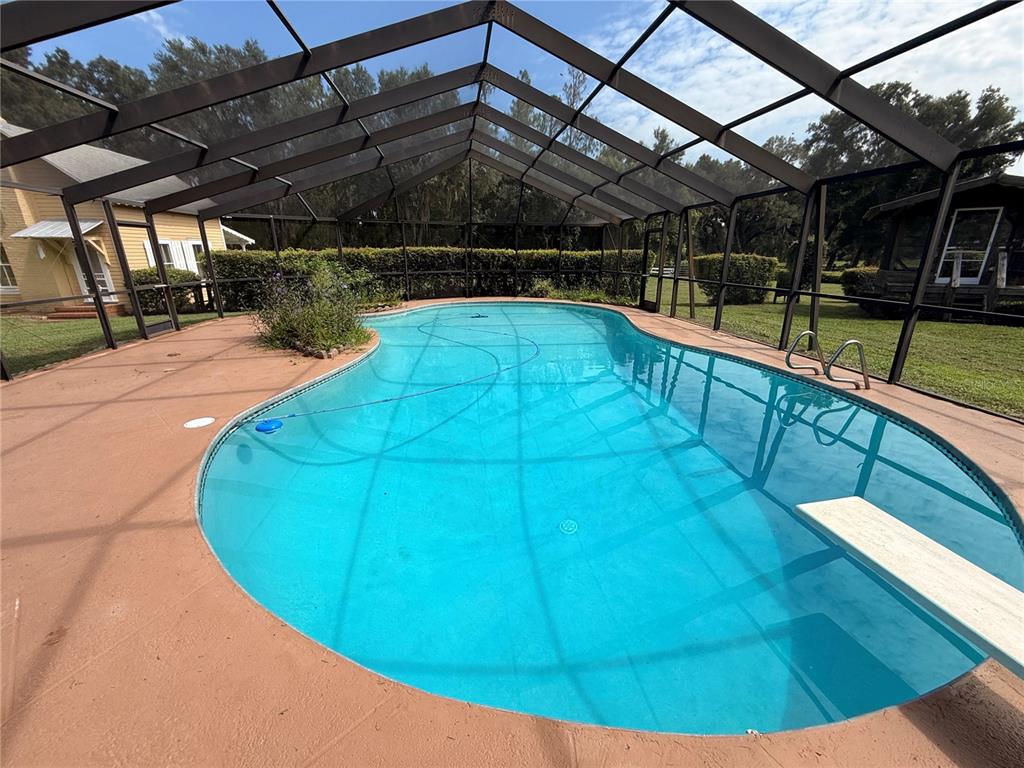 A tan, single-story house with a metal-roofed porch and a stone walkway in a yard — 34951 EASTERLING ROAD, DADE CITY, FL