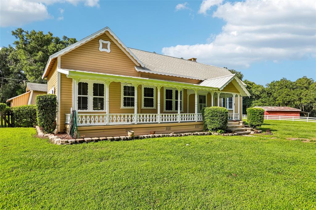 A tan, single-story farmhouse with a wrap-around porch sits on a large, grassy lawn — 34951 EASTERLING ROAD, DADE CITY, FL