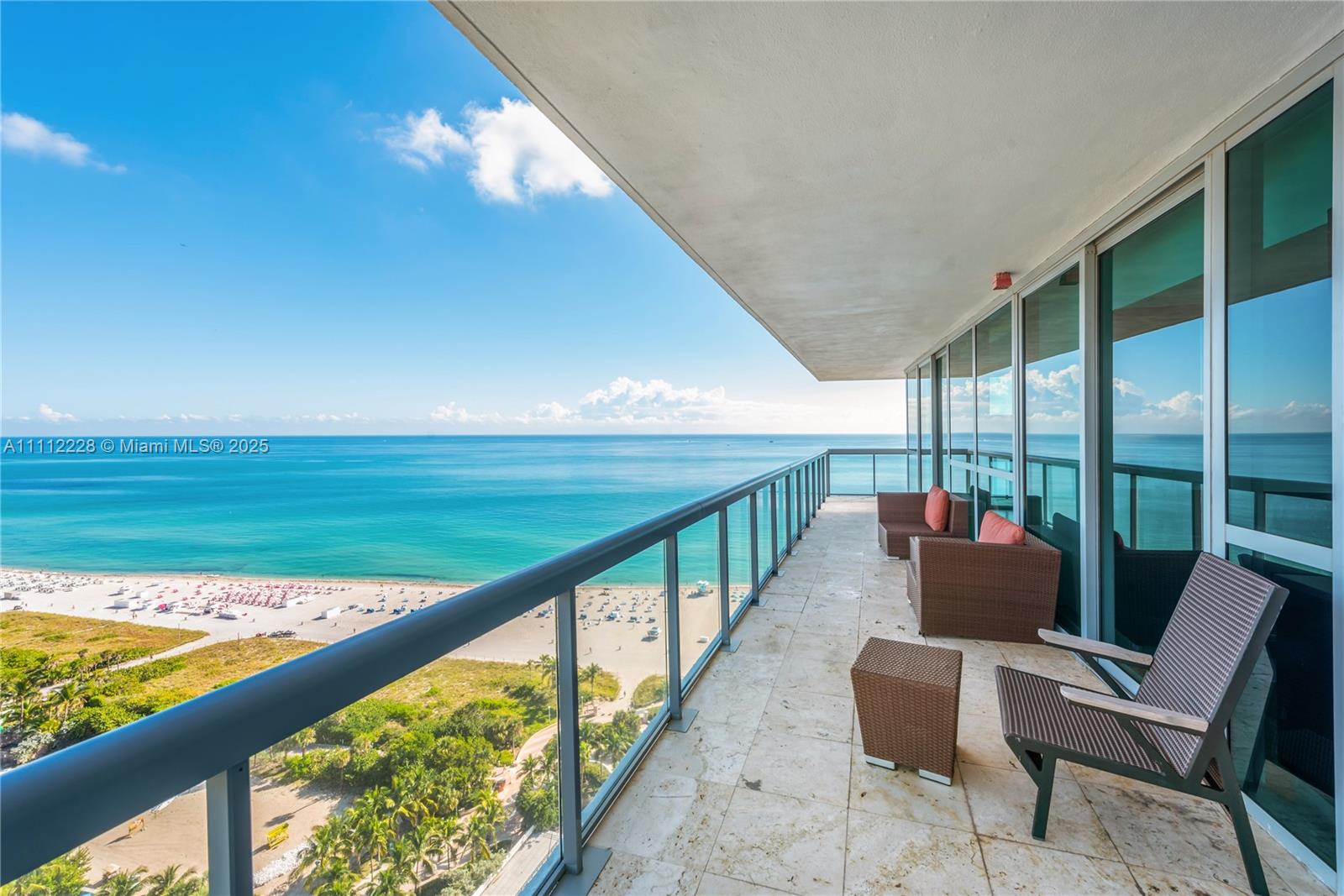 A high-rise balcony features tile flooring, glass railings, and outdoor furniture overlooking the beach — 101 20th St # 2707, Miami Beach FL 33139, MIAMI BEACH, FL