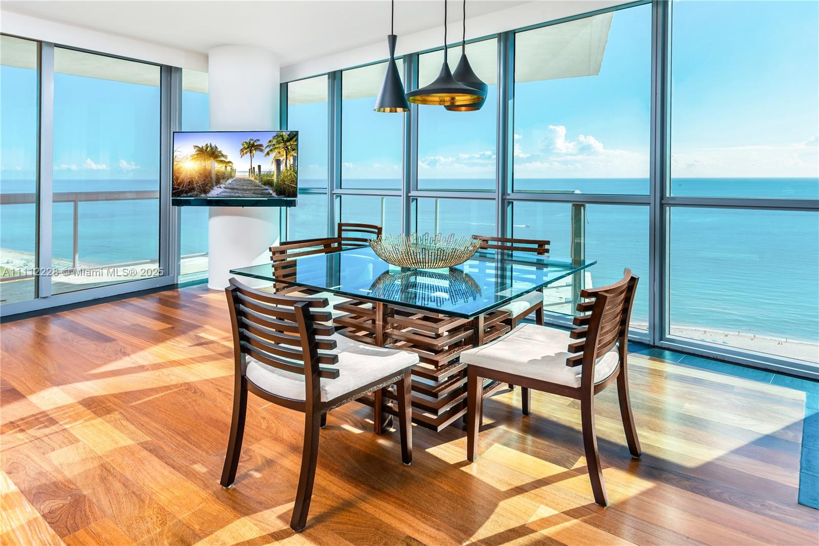 A dining room features a glass-topped table, wooden chairs, and floor-to-ceiling windows overlooking the ocean — 101 20th St # 2707, Miami Beach FL 33139, MIAMI BEACH, FL