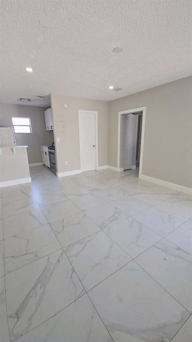 A bright room with white marble-patterned tile flooring, a kitchen area, and two doorways — 616 NW 5th Avenue # 2, Pompano Beach FL 33060, POMPANO BEACH, FL