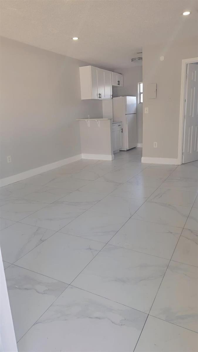 A bright, open-concept room features white marble-look tile flooring and a small kitchen area — 616 NW 5th Avenue # 2, Pompano Beach FL 33060, POMPANO BEACH, FL