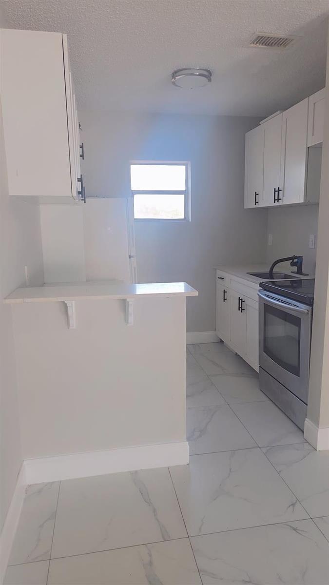 A kitchen features white cabinets, stainless steel appliances, and light-colored tile flooring — 616 NW 5th Avenue # 2, Pompano Beach FL 33060, POMPANO BEACH, FL
