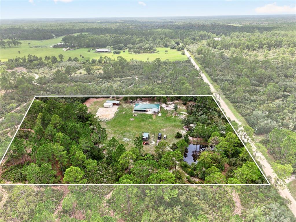 An aerial view shows a house with a green roof, outbuildings, and a pond — 10550 SW 52ND PLACE, CEDAR KEY, FL
