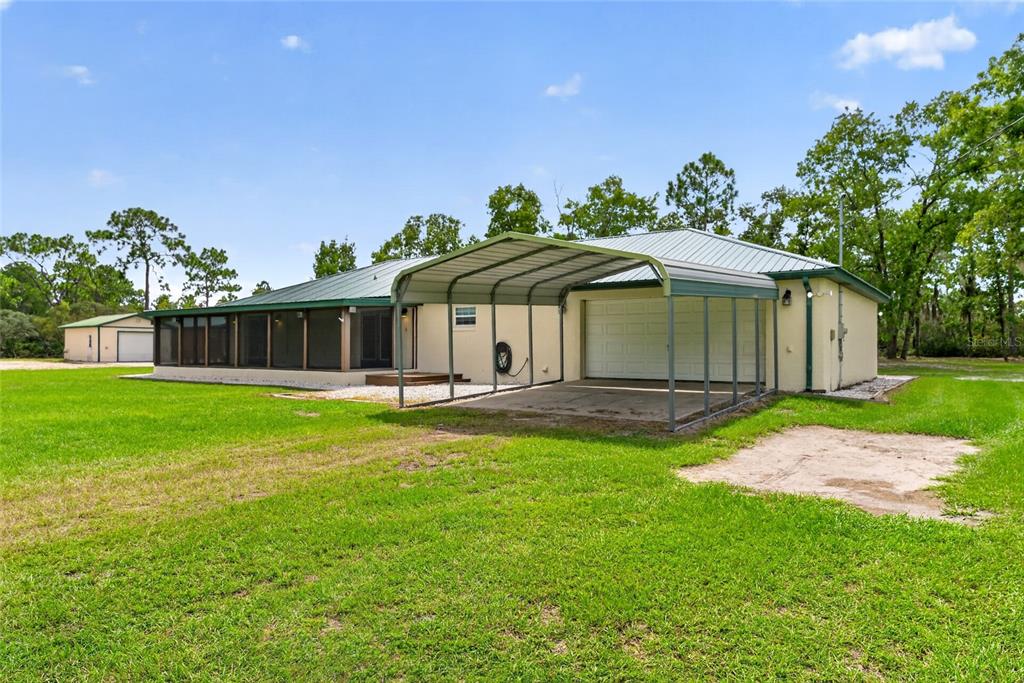 A single-story house with a metal carport, a screened-in porch, and a detached garage — 10550 SW 52ND PLACE, CEDAR KEY, FL