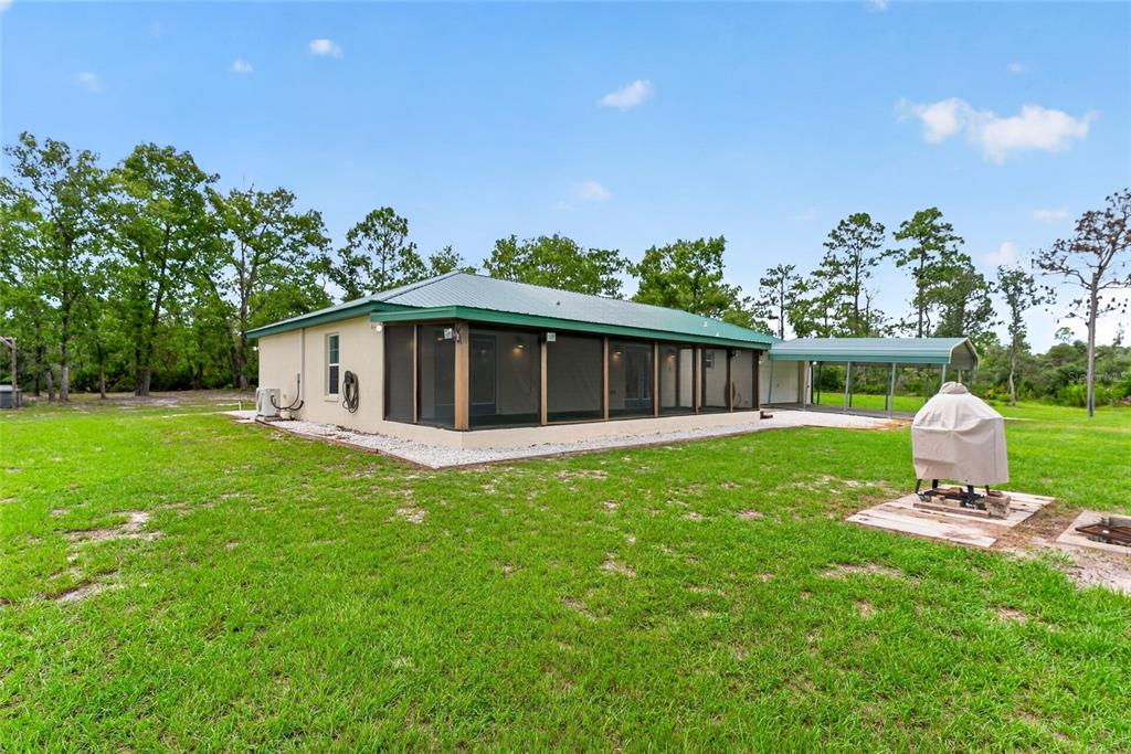 The exterior of a single-story house features a screened-in porch, metal roof, and carport — 10550 SW 52ND PLACE, CEDAR KEY, FL