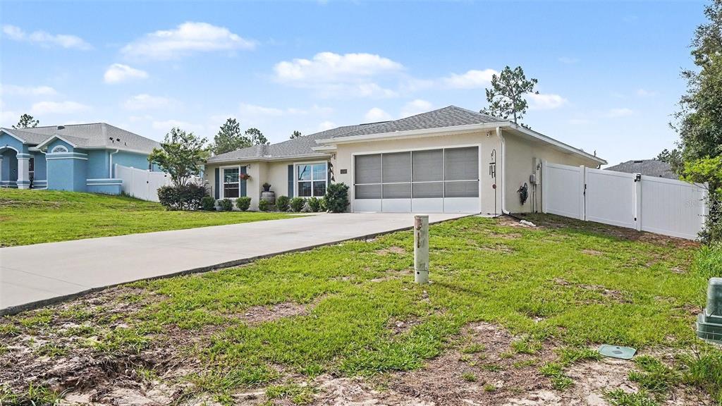 A single-story house with a concrete driveway, a screened garage door, and a white fence — 6548 SW 131ST PLACE, OCALA, FL